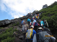7合目を鎖で登る登山者の写真